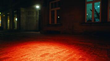 vaag beeldmateriaal onthult een rood licht gieten een gloed Aan de geplaveide straat buiten een gebouw Bij nacht video