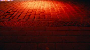 Dreamlike video showcases the ethereal glow of a red light on the cobblestone street outside a building at night