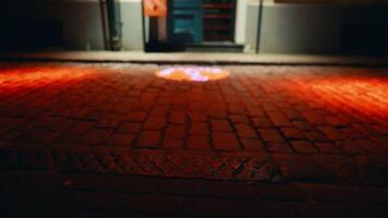 Hazy recording provides a glimpse of the atmospheric red light on the cobblestone street outside a building at night video