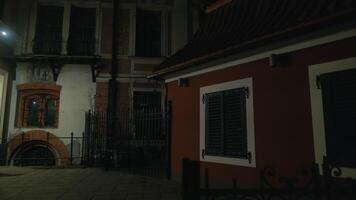 Red building with black window shutters illuminated at night video