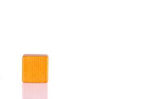 Wooden cube of orange color on a white background photo