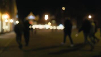 Blurry image of pedestrians on dark street at night lit by car headlights video