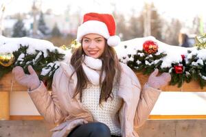 Winter portrait young adult beautiful woman in Santa hat. Christmas mood. Snowing. Winter beauty fashion concept photo