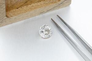 macro mineral faceted stone Morganite with tweezers on a gray background photo