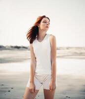 Young pretty red-haired woman standing on the beach photo