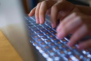 Close up image of hands typing on laptop computer keyboard and surfing the internet at home. Freelancer copywriter working project, typing text, edit something. Remote job concept photo