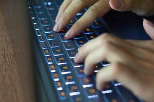 Close up image of hands typing on laptop computer keyboard and surfing the internet at home. Freelancer copywriter working project, typing text, edit something. Remote job concept photo