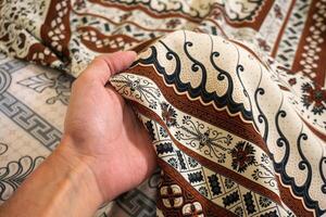 A hand holding traditional Indonesian fabric, namely batik cloth. Indonesia with elegant classic motif photo