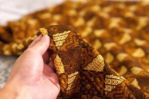 A hand holding traditional Indonesian fabric, namely batik cloth. Indonesia with elegant classic motif photo