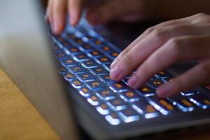 Close up image of hands typing on laptop computer keyboard and surfing the internet at home. Freelancer copywriter working project, typing text, edit something. Remote job concept photo