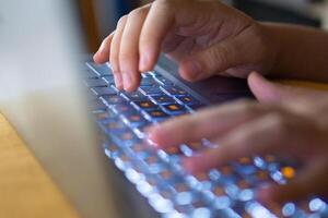 Close up image of hands typing on laptop computer keyboard and surfing the internet at home. Freelancer copywriter working project, typing text, edit something. Remote job concept photo