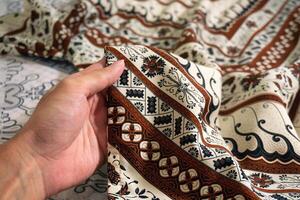 A hand holding traditional Indonesian fabric, namely batik cloth. Indonesia with elegant classic motif photo