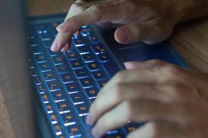 Close up image of hands typing on laptop computer keyboard and surfing the internet at home. Freelancer copywriter working project, typing text, edit something. Remote job concept photo