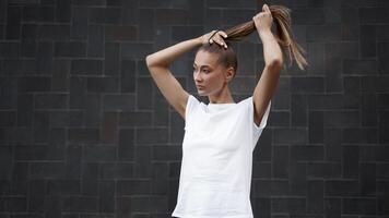 Woman Ties her hair in a ponytail before morning workout black wall background photo