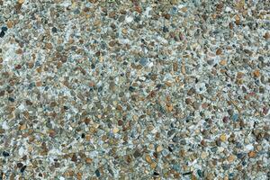 Pebble stone floor tile seamless background. Cement mixed gravel pebble stone floor texture. Wet round pebble stone rock floor in dramatic lighting. photo