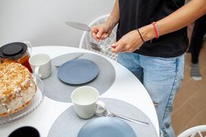 de cerca de hembra manos participación pastel espátula y tenedor. en el mesa es un pastel, platos y tazas. hecho en casa té fiesta foto