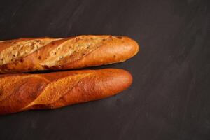 Two crispy french baguettes lie on an old wooden table with free space for text photo