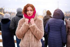 joven hermosa pelirrojo niña pecas hielo pista en antecedentes. bonito mujer Rizado pelo retrato caminando en nuevo año justa foto