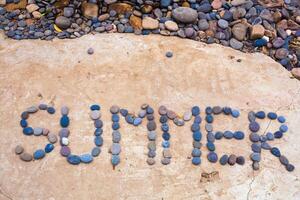 inscription on a plate lined with small stones of summer sea photo