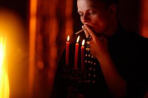 Young adult caucasian catholic priest on dark red background photo