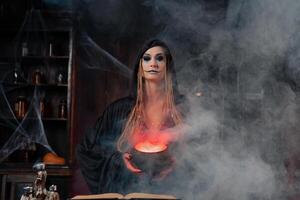 Víspera de Todos los Santos, bruja utilizar magia libro y caldera preparar veneno o amor poción foto