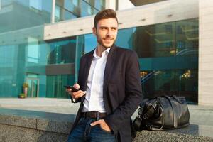 Young urban professional man using smart phone. Businessman holding mobile smartphone using app texting sms message wearing jacket photo