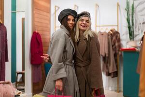 Two women girlfriends in a fashion boutique choose a coat for autumn season. photo