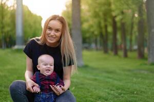 Beautiful young mother walks with her little son in a summer park photo