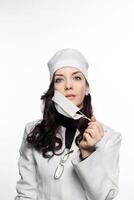 a woman in a white coat holding her mask photo