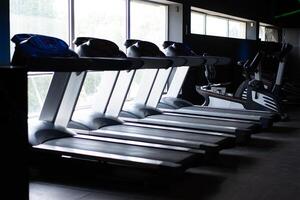 Empty treadmill standing gym near big window photo