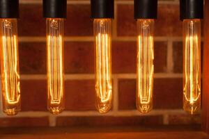 Light bulb lamp on dark red brick background with hotspot close up loft photo