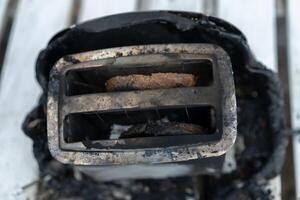 Burning toaster. Toaster with two slices of toast caught on fire over white background photo