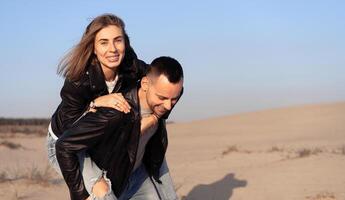 Happy and cute adorable adult couple of millennial hipsters, man with woman girlfriend on piggy back, have fun play photo