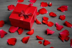 Beautiful red roses next to a gift red box on a dark cement background. photo