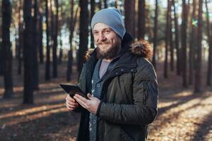 cerca arriba retrato de adulto masculino caminante utilizando digital lengüeta y mirando para ubicación durante caminata en naturaleza. hombre en caminata utilizando digital tableta para navegación. foto