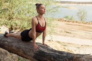 Young woman in red sport top practicing yoga in beautiful nature. Meditation in morning sunny day photo