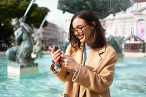 mujer en lentes utilizando teléfono inteligente al aire libre foto