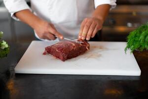 unrecognizable young African chef standing in professional kitchen in restaurant preparing a meal of meat and cheese vegetables. photo