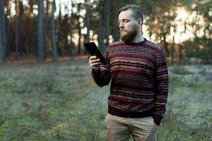 Portrait of adult man walking in the pine forest with digital tablet. photo