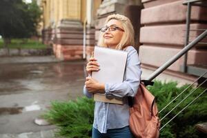 Enthusiastic Happy beautiful young girl smiling and holding pile of books standing near campus lifestyle positivity academic graduating university school photo