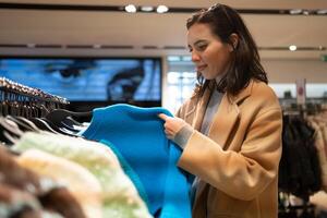 Woman choose what to buy in clothes store photo