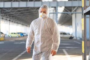 COVID-19 coronavirus doctor standing hospital parking dressed white protective overalls hazmat suit. photo