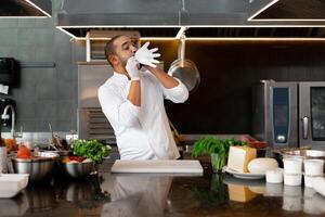 joven atractivo masculino cocinar golpes arriba su protector guante chistes y tiene divertido en el profesional cocina foto