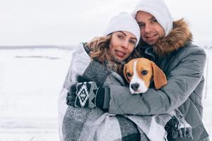 Happy couple at the winter landscape Happy family with beagle dog. Winter season photo