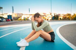 Tired happy woman runner taking rest after run sitting running track photo