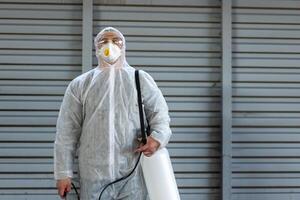 trabajador vistiendo protector traje desinfección engranaje desinfectar superficie público sitio foto