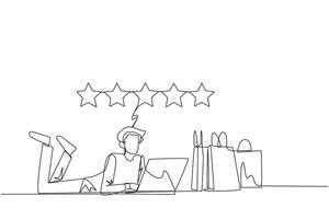 Continuous one line drawing young smiling man on stomach while typing on laptop. Next to the laptop is a shopping bag. Give the best review with pleasure. Single line draw design vector illustration