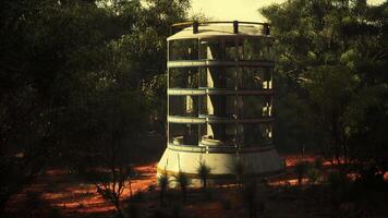 bicchiere serra Torre nel il mezzo di un' lussureggiante campo circondato di alberi video