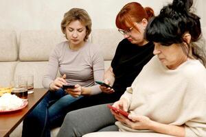 women on the sofa sitting on their phones photo