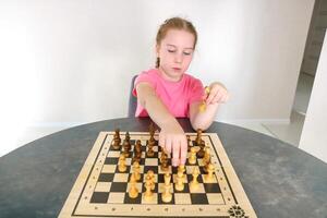 girl makes moves with pieces on the chessboard photo